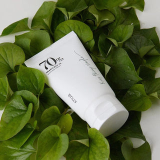 Anua Heartleaf 70% Soothing Cream tube placed above a bunch of leaves
